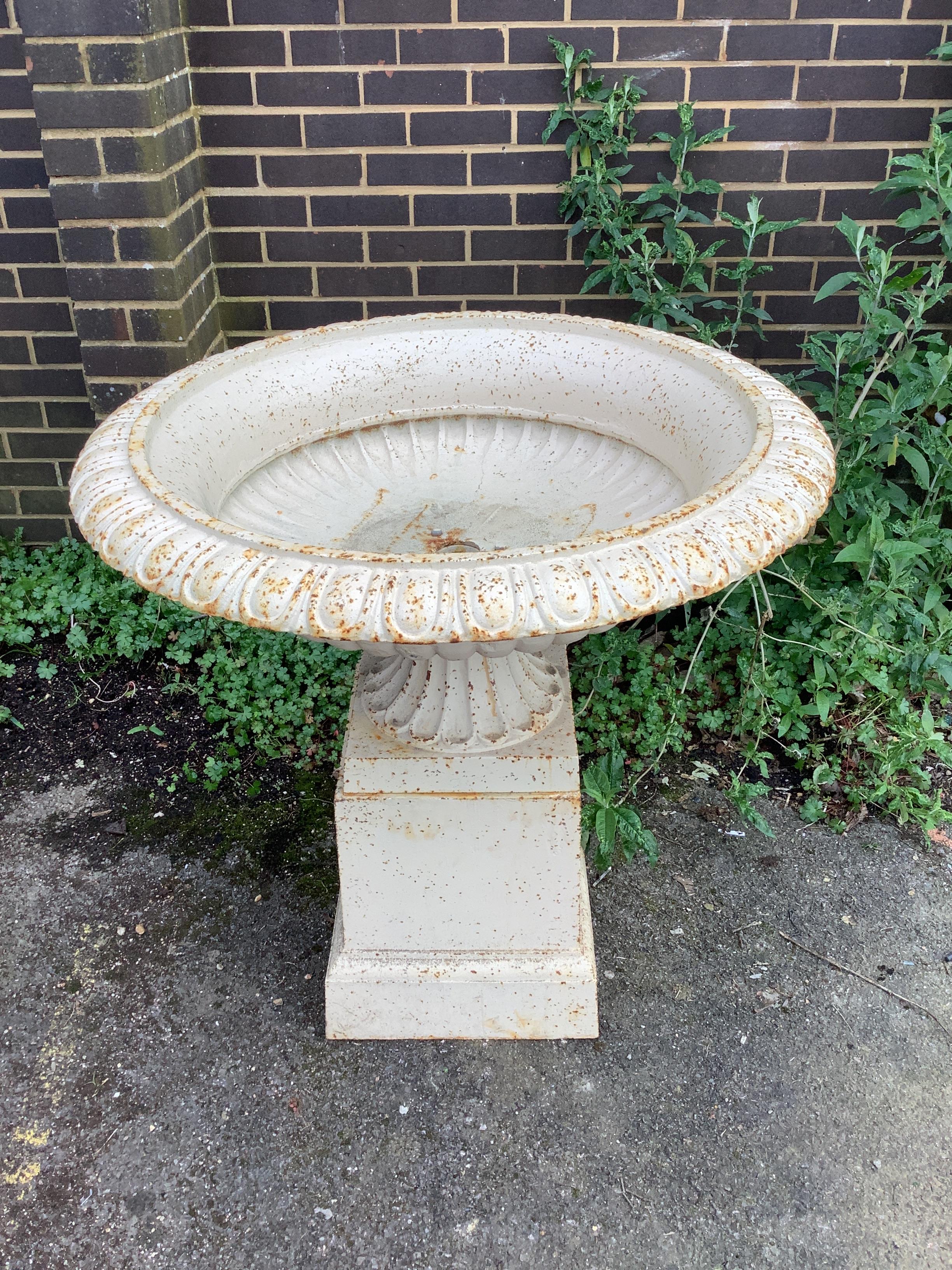 A Victorian style circular cast iron campana garden urn on square plinth, diameter 95cm, height 95cm